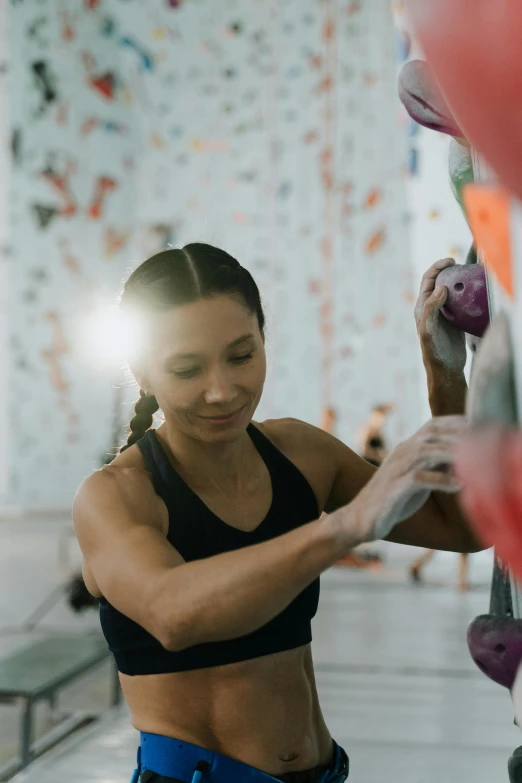 a woman standing in front of a climbing wall, profile image, partially cupping her hands, working out, slight glow