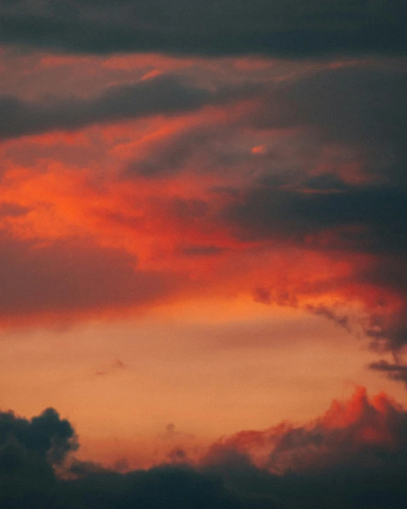 a plane flying through a cloudy sky at sunset, an album cover, pexels contest winner, romanticism, ☁🌪🌙👩🏾, the sky is a faint misty red hue, cloud iridescence, red cloud