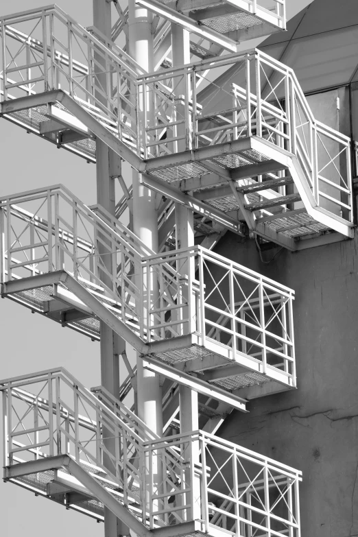 a black and white photo of a fire escape stairs, inspired by André Kertész, constructivism, chemical plant, square, industrial colours, white steel