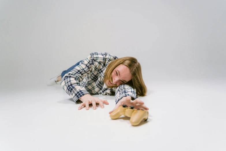 a man laying on the ground next to a pair of shoes, inspired by Sarah Lucas, ricky berwick, press shot, stuffed toy, holding a wood piece