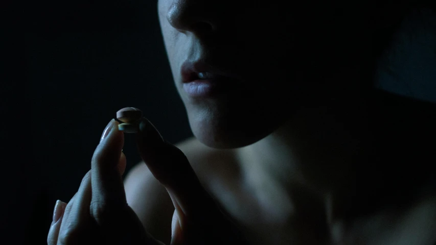 a close up of a person holding a cell phone, inspired by Elsa Bleda, offering the viewer a pill, 8 k sensual lighting, filmstill, dark
