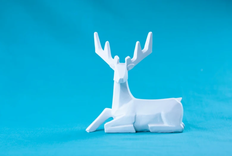 a white paper sculpture of a deer on a blue background, inspired by Rudolph F. Ingerle, unsplash, horse laying down, mini figure, glossy white, resting