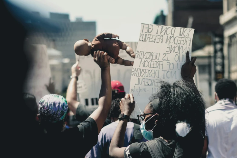 a group of people holding up signs in the air, a photo, by Emma Andijewska, trending on pexels, man is with black skin, tear gas, cel - shaded, 2 0 5 6