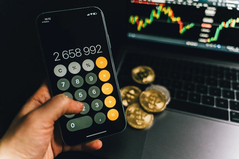 a person holding a calculator in front of a laptop, a photo, by Julia Pishtar, trending on pexels, pixel art, bitcoin, photograph credit: ap, liquid gold, taken on an iphone