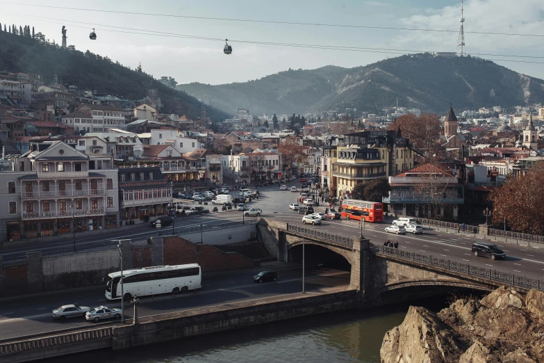 a city filled with lots of traffic next to a river, a photo, by Matija Jama, pexels contest winner, renaissance, bosnian, trams ) ) ), hills, old bridge