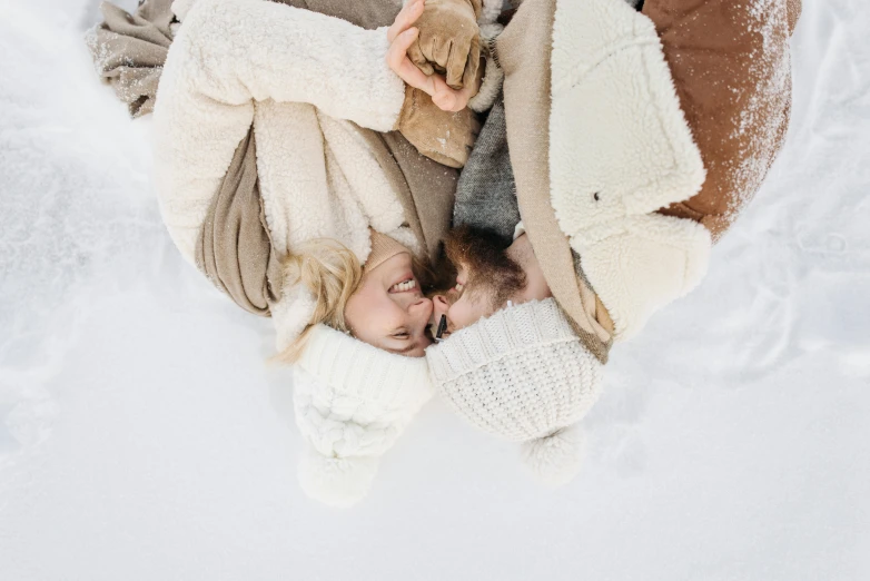 a woman and a child laying in the snow, trending on pexels, romanticism, lined in cotton, tan, romantic couple, gif