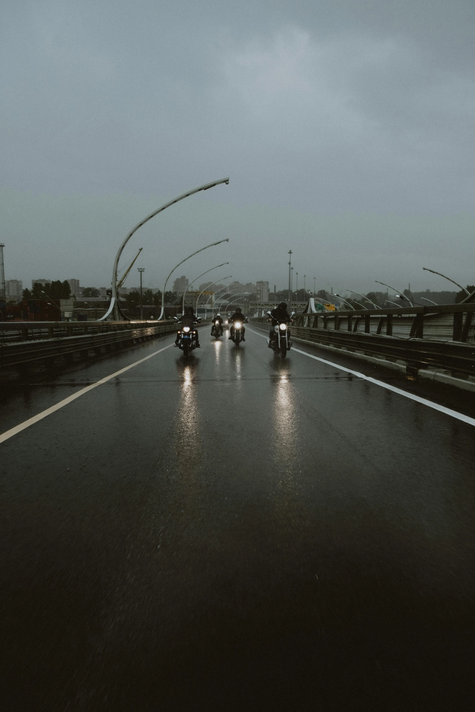 a group of motorcyclists riding down a highway in the rain, unsplash contest winner, conceptual art, bridge, extremely gloomy lighting, low quality photo, depressing image