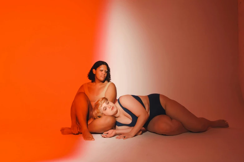 a couple of women laying on top of each other, an album cover, unsplash, full figured, orange body, full body image, broad light