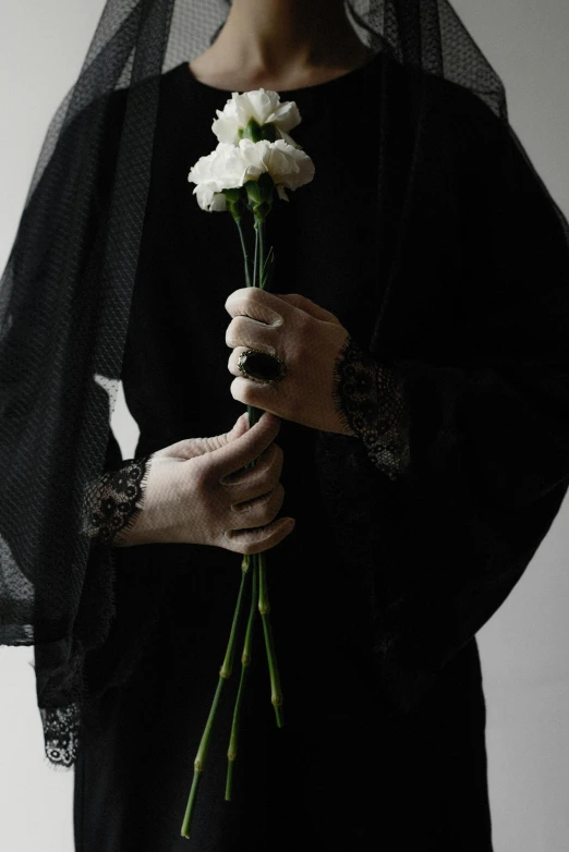 a woman in a black dress holding a white carnation, by Maryam Hashemi, unsplash, romanticism, burka, showstudio, cai xukun, devils