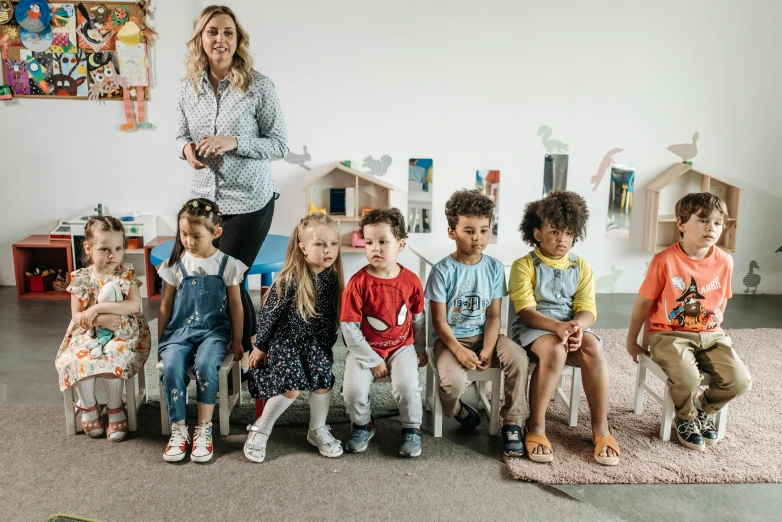 a woman standing in front of a group of children, by Arabella Rankin, art & language, sitting down, jovana rikalo, professionally taken, discovery zone