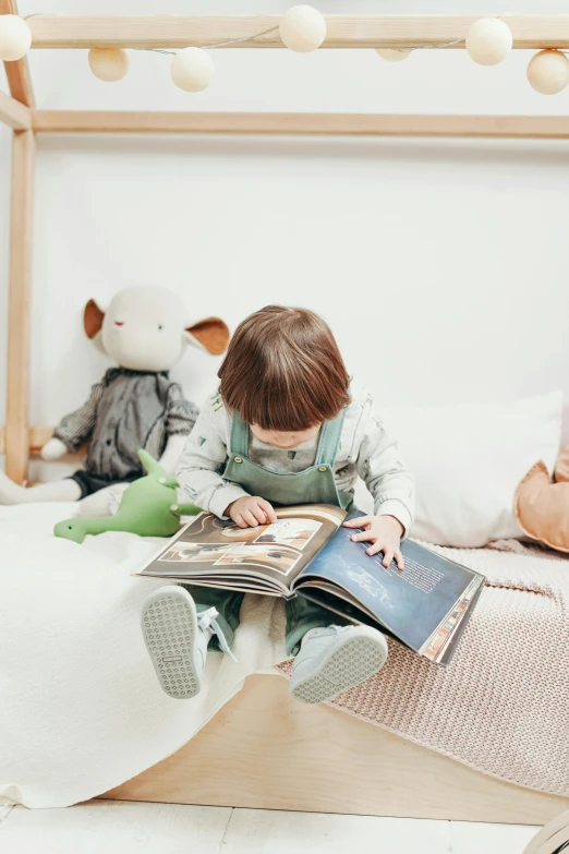 a little boy sitting on a bed reading a book, pexels contest winner, stuffed animal, looking partly to the left, gif, grey
