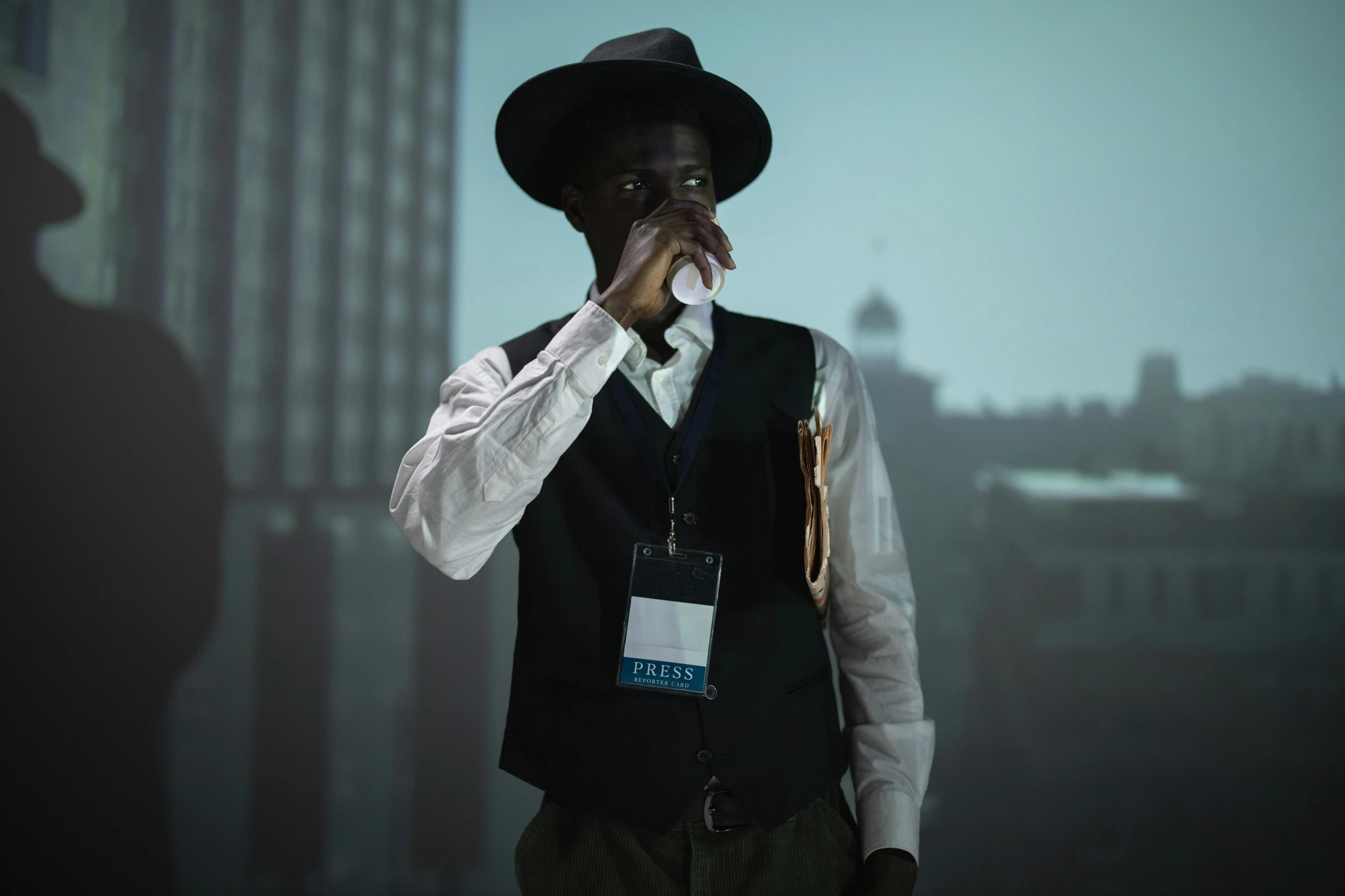 a man in a hat and vest smoking a cigarette, inspired by Gordon Parks, pexels contest winner, in front of a sci fi cityscape, black man, award winning movie still, under a spotlight