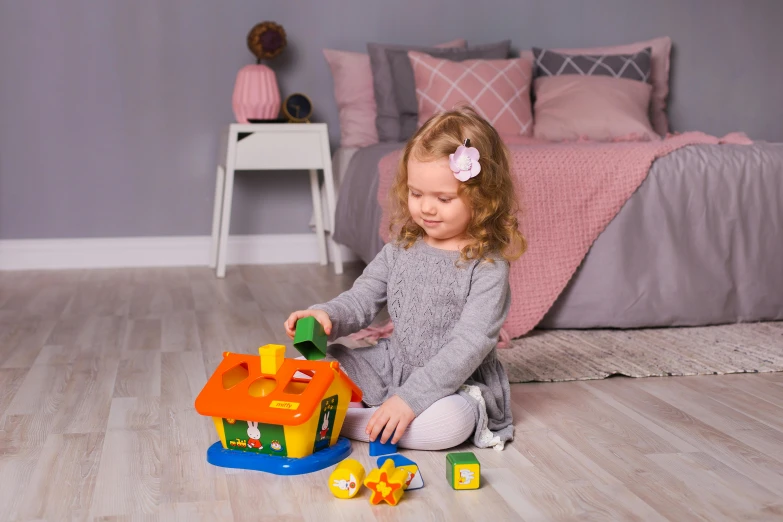 a little girl sitting on the floor playing with a toy house, inspired by Nicolas Poussin, happy meal toy, multicoloured, official product photo, highlights