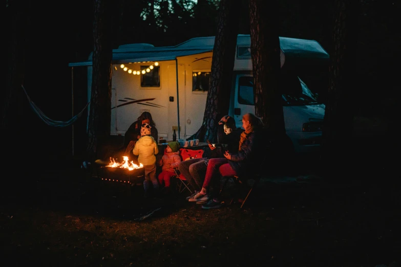 a group of people sitting around a fire pit, caravan, complementary rim lights, profile image, spooky photo