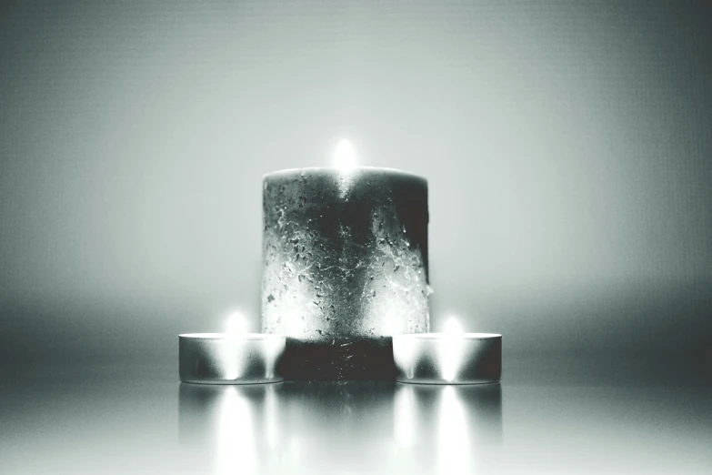 a couple of candles sitting on top of a table, a black and white photo, by Adam Marczyński, made of glowing wax, highkey, ((monolith)), light reflection