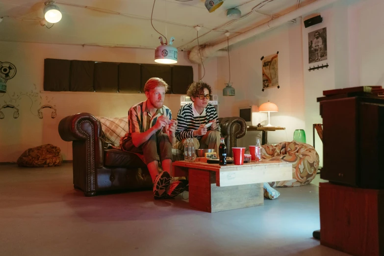 two people sitting on a couch in a living room, by Lee Gatch, unsplash, visual art, performing a music video, diner, joel fletcher, soda