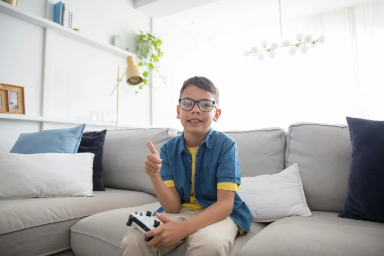 a boy sitting on a couch holding a video game controller, square rimmed glasses, 15081959 21121991 01012000 4k, high quality picture, with glasses on