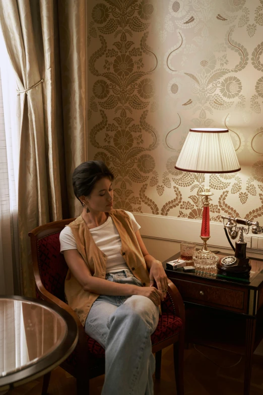 a woman sitting in a chair next to a lamp, hotel room, in the white house, environmental shot, concerned