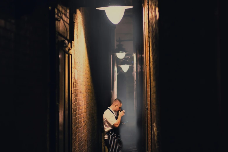 a man standing in a hallway talking on a cell phone, by Nick Fudge, pexels contest winner, fantastic realism, michelin starred restaurant, in an alley at night back lit, in front of smoke behind, press shot