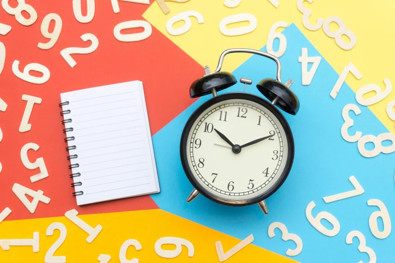 a clock sitting on top of a table next to a notebook, multicoloured, thumbnail, educational supplies, 8 h