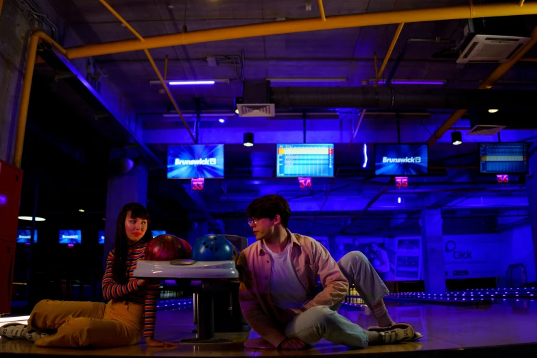 a couple of people sitting next to each other on a stage, unsplash, conceptual art, bowling, 8 0 s asian neon movie still, purple and yellow lighting, perfect blue