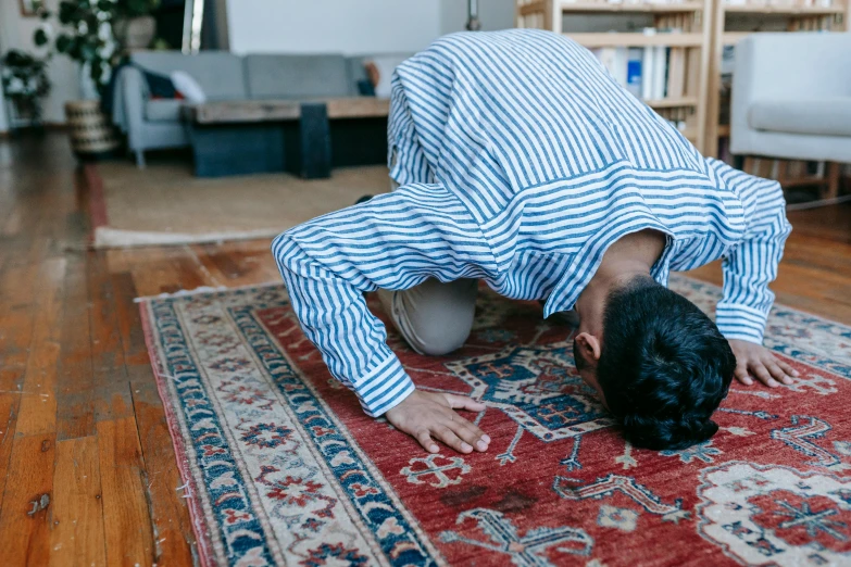 a man doing a handstand on a rug in a living room, pexels contest winner, hurufiyya, kneeling in prayer, asian male, middle eastern skin, on a checkered floor