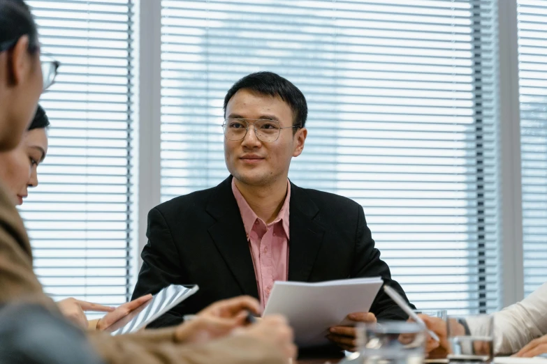 a group of people sitting around a table, jeremy cheung, in an office