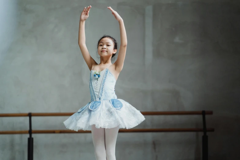 a young ballerina is practicing her ballet moves, pexels contest winner, arabesque, costume with blue accents, young asian girl, blank, joy ang