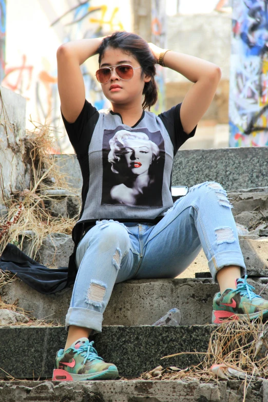 a woman sitting on the steps of a building, instagram, pop art, jeans and t shirt, young himalayan woman, in tshirt, torn!! clothing