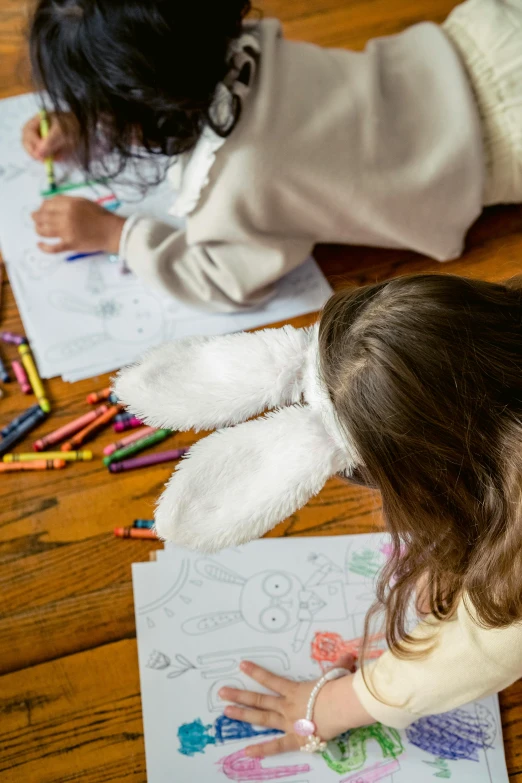 a couple of little girls sitting on top of a wooden floor, a child's drawing, inspired by Maurice Sendak, pexels contest winner, drooping rabbity ears, colouring - in sheet, thumbnail, holiday season