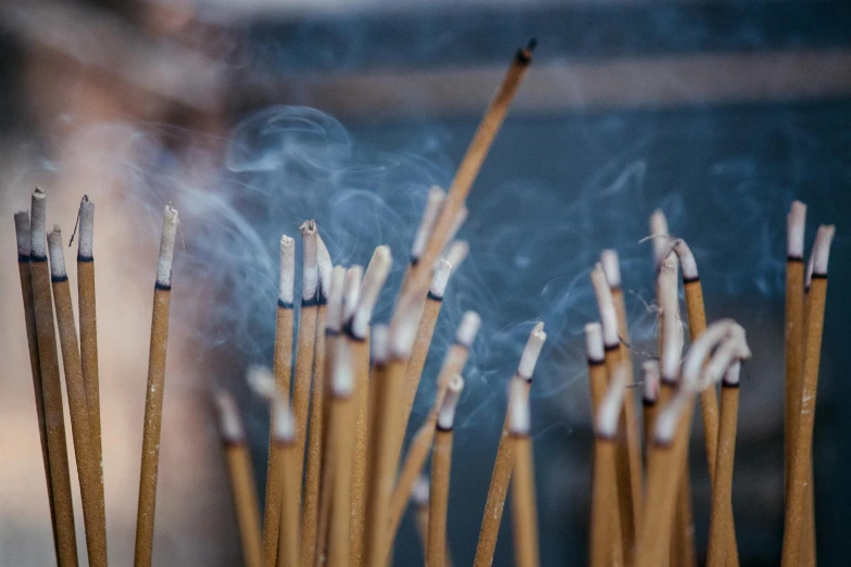 a close up of a bunch of incense sticks, trending on unsplash, tiny smokes from buildings, spiritual scene, paul barson, indigo