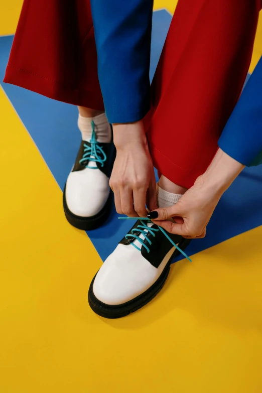 a person tying up a pair of shoes, inspired by Okuda Gensō, trending on pexels, de stijl, preppy style, studio shot, teals, close up portrait shot