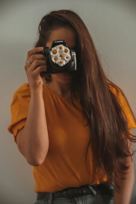 a woman taking a picture of herself with a camera, inspired by Elsa Bleda, pexels contest winner, wearing yellow floral blouse, she has long orange brown hair, minimalist photorealist, highly detailed # no filter