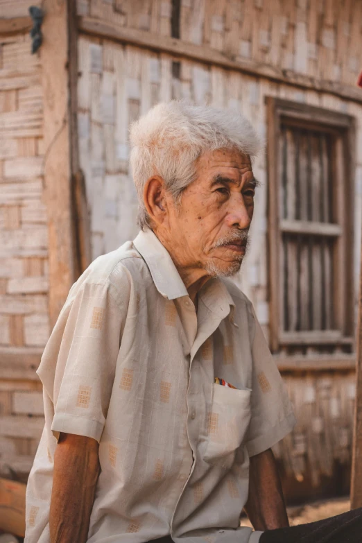 an old man sitting in front of a building, pexels contest winner, mingei, wearing a linen shirt, profile image, standing outside a house, asian human