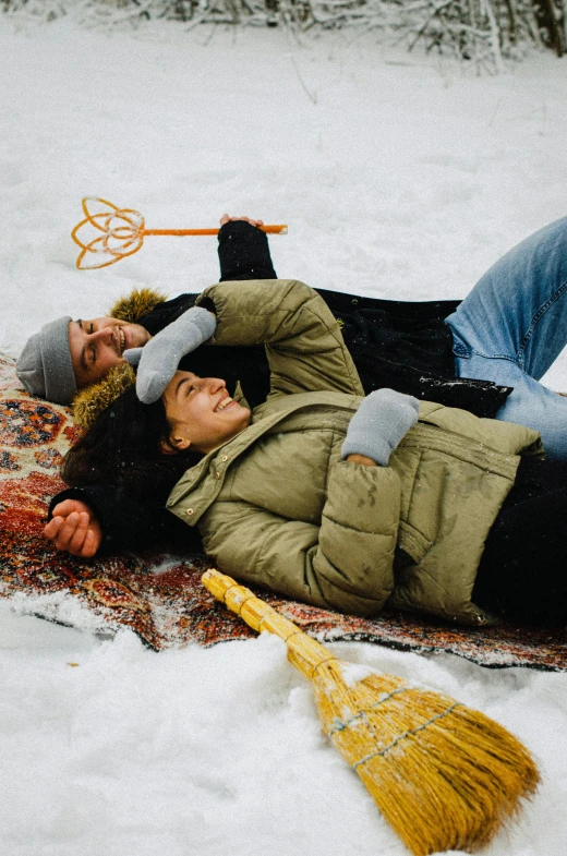 a person laying in the snow with a broom, pexels contest winner, happy couple, islamic, tubing, lesbians