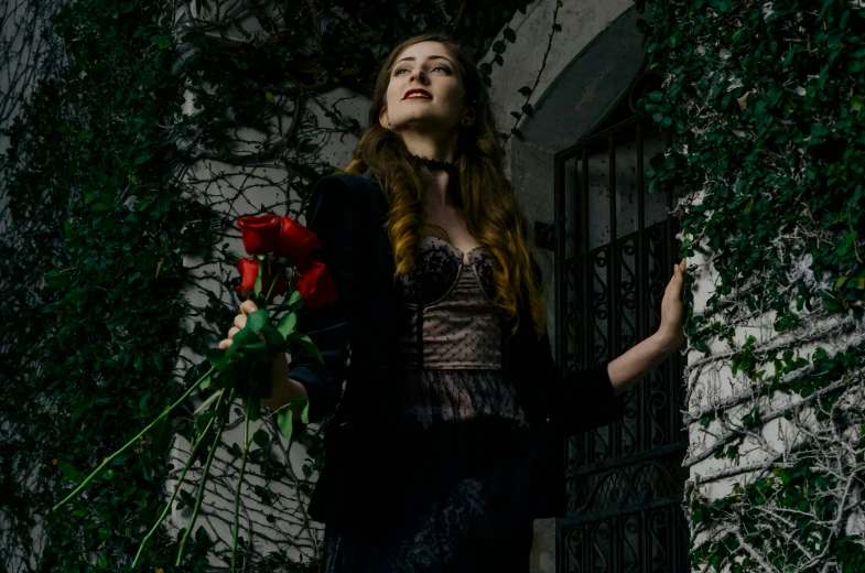 a woman standing in front of a building holding a rose, an album cover, inspired by Elsa Bleda, pexels contest winner, renaissance, black gothic jacket, red roses, profile image, pose 4 of 1 6