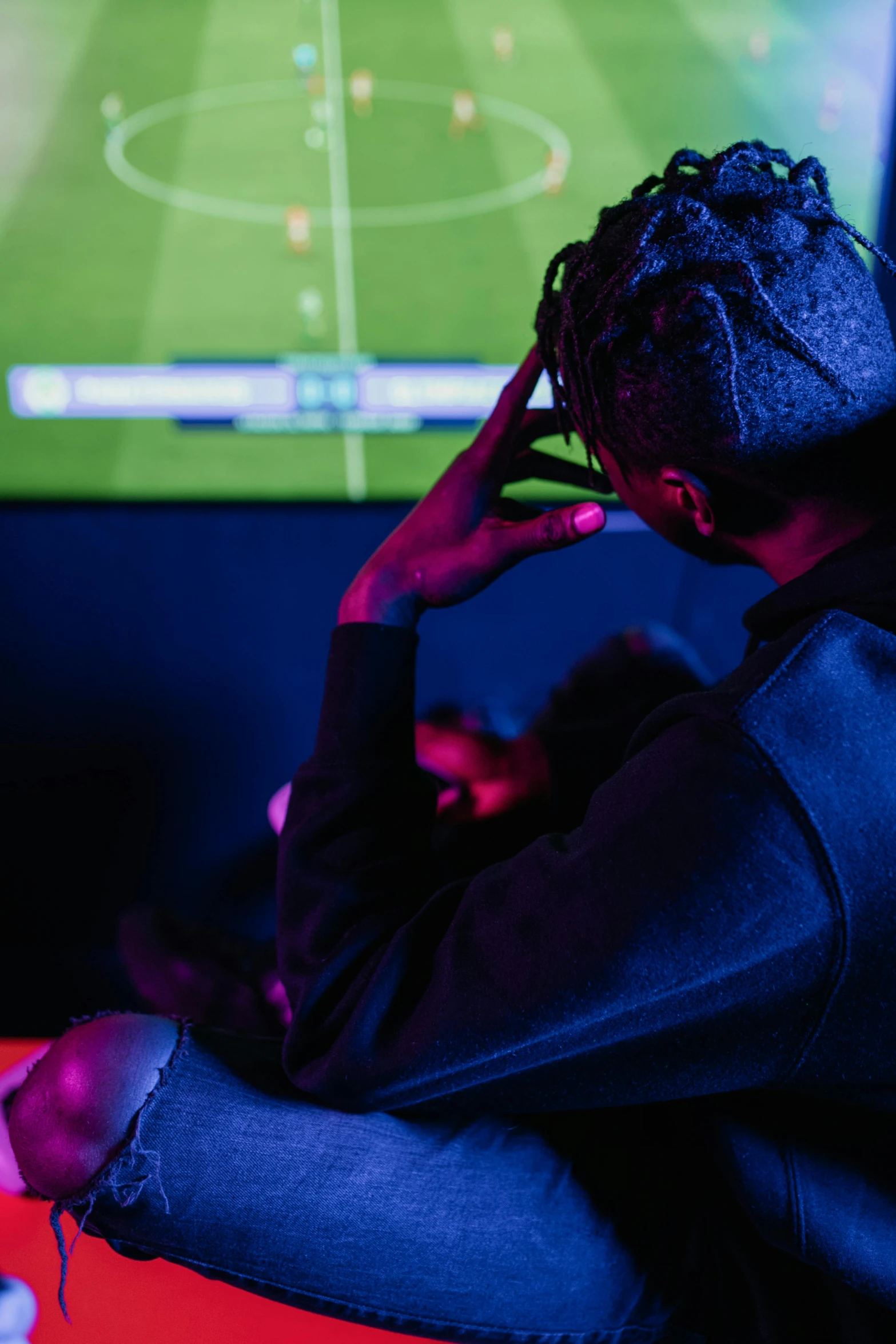 a man sitting in front of a tv playing a video game, soccer, chillin at the club together, afro tech, f/1.4