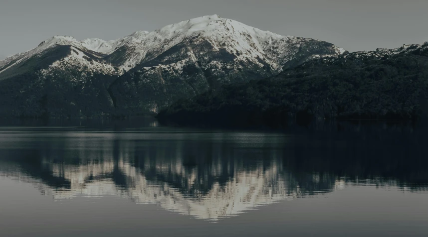 a large body of water with a mountain in the background, pexels contest winner, snowy craggy sharp mountains, mirrored, dark and white, low detailed