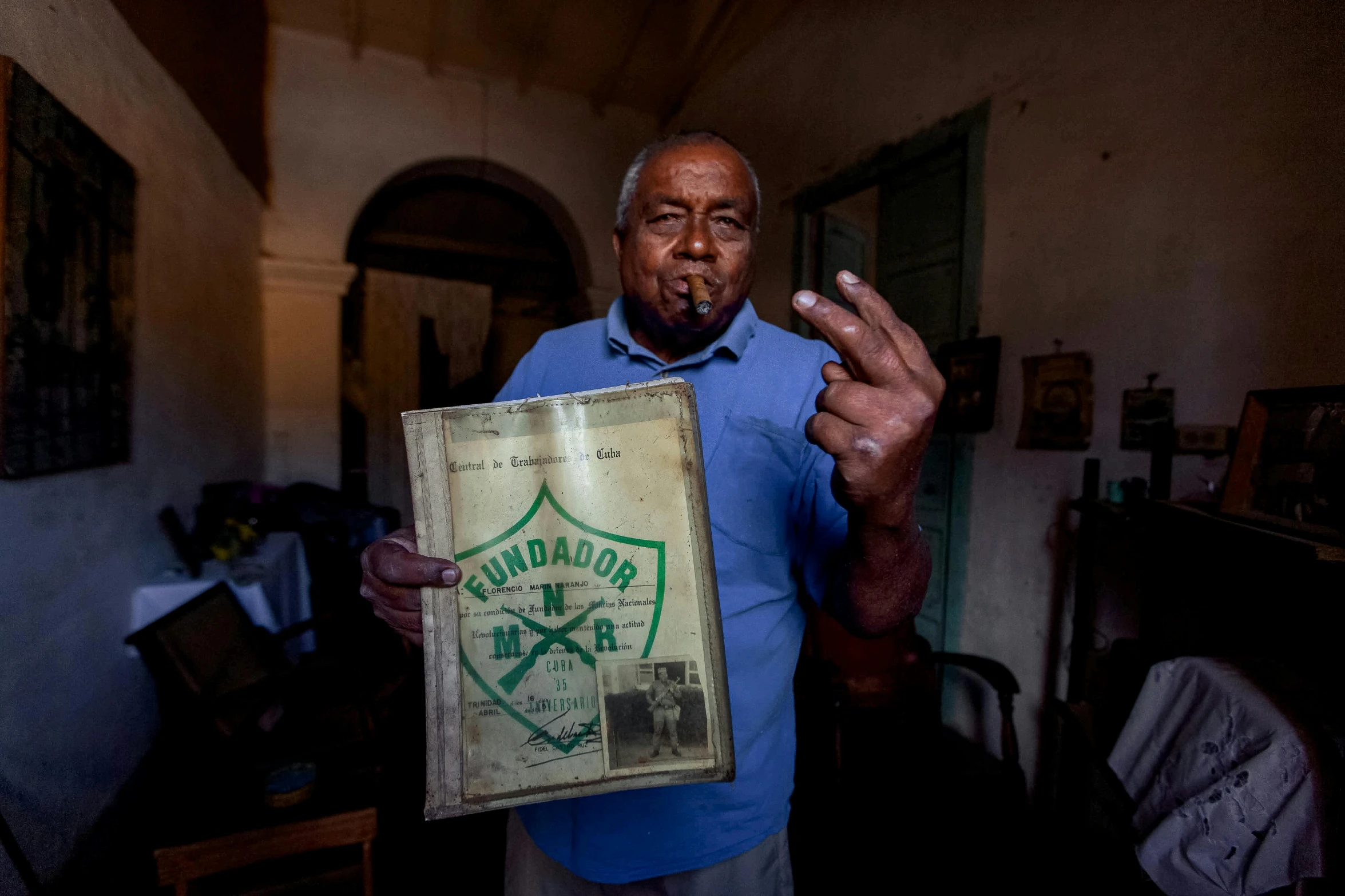 a man standing in a room holding a sign, a portrait, pexels contest winner, dada, cuba, holding khopesh and shield, smokes, portrait image