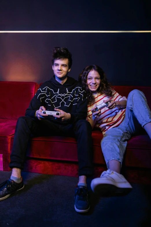 a man and a woman sitting on a red couch, by John Luke, holding controller, posing for a picture, high light on the left, gabriel hardman