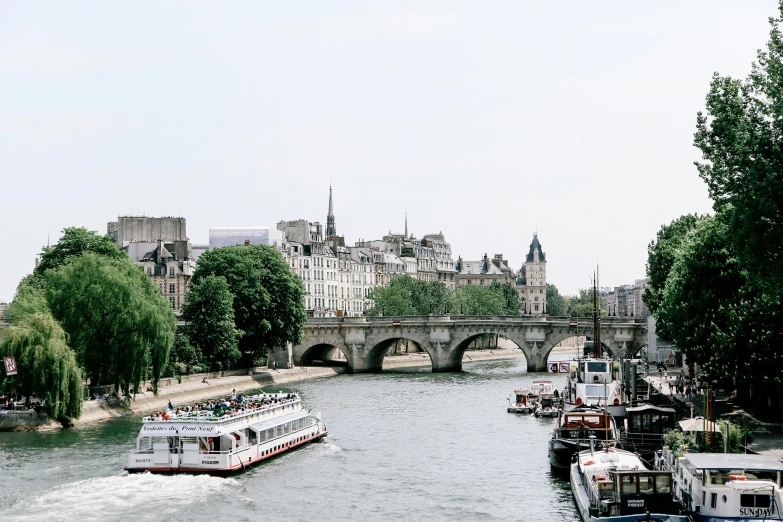 a group of boats traveling down a river next to a bridge, by Raphaël Collin, pexels contest winner, visual art, paris background, white buildings, fine art print