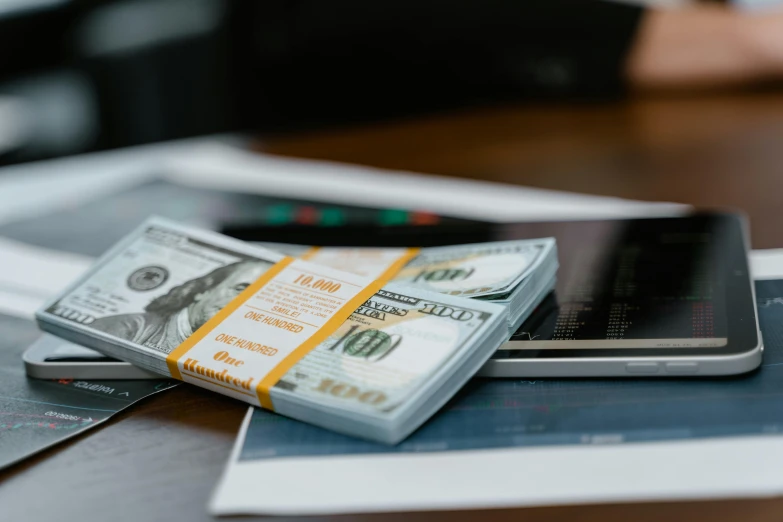 a pile of money sitting on top of a table next to a cell phone, on a desk, thumbnail, wētā fx, offset