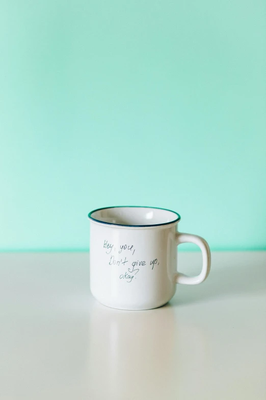 a close up of a cup on a table, by Tracey Emin, unsplash, you grow. then you focus on shit, white and teal metallic accents, hero shot, hey buddy