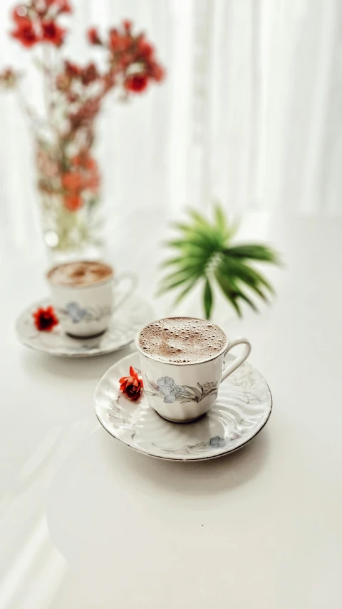 a couple of cups of coffee sitting on top of a table, inspired by Niyazi Selimoglu, arabesque, silver mist, - 6, with a cup of hot chocolate, at home