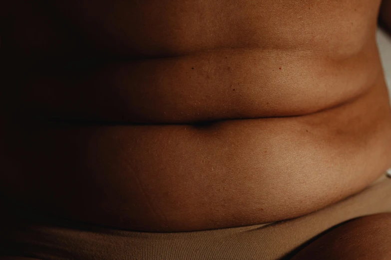 a close up of a person sitting on a bed, by Elsa Bleda, trending on pexels, renaissance, her belly is fat and round, abdominal muscles, realistic textured skin, failed cosmetic surgery