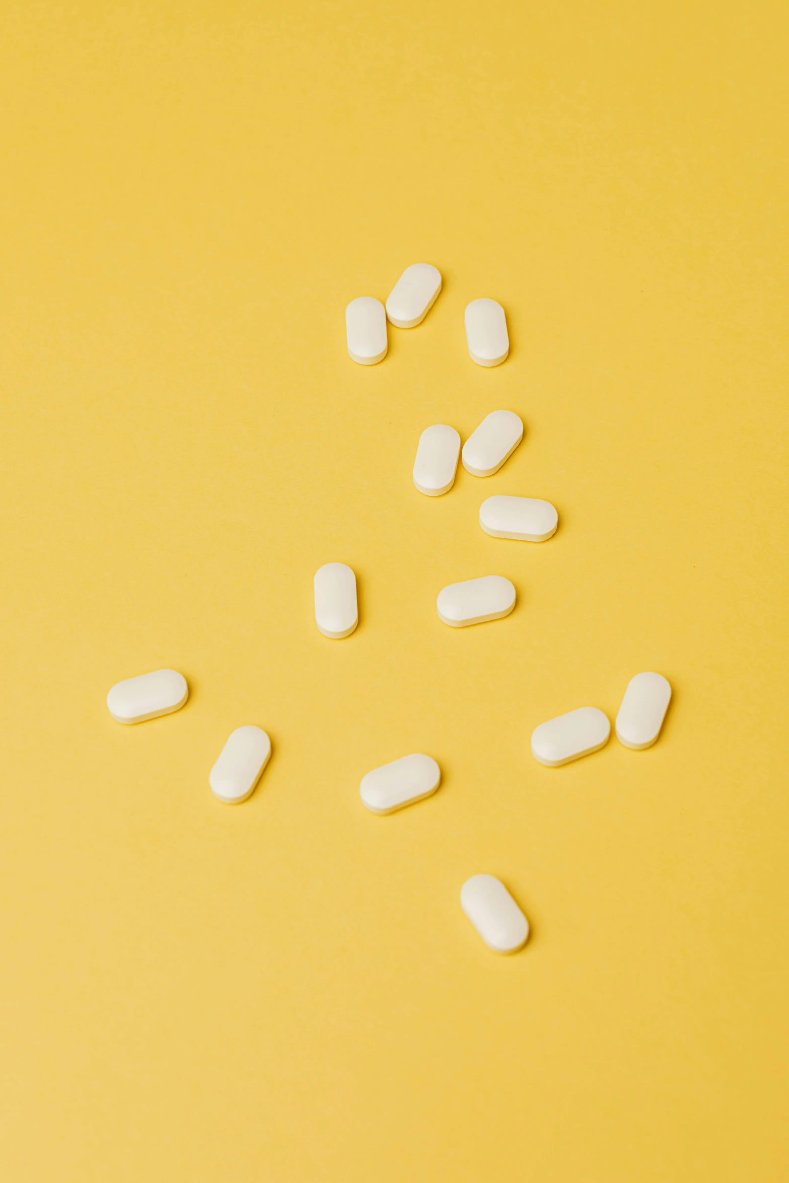 white pills scattered on a yellow background, by Jessie Algie, unsplash, antipodeans, product shoot, vanilla, multiple stories, open synthetic maw