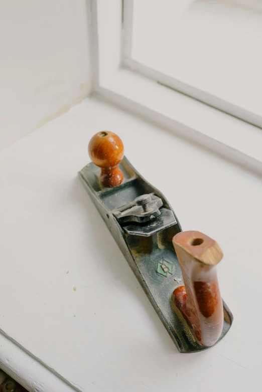 a small plane sitting on top of a window sill, a surrealist sculpture, by Doug Ohlson, unsplash, mingei, workbench, wooden boat, tools, midcentury modern