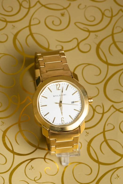 a close up of a watch on a table, an album cover, shutterstock contest winner, made in gold, bulgari, white: 0.5, made of gold