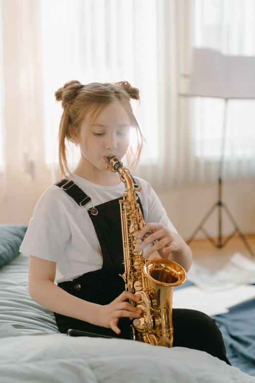 a little girl sitting on a bed playing a saxophone, pexels contest winner, girl wearing uniform, shorter neck, resin, trending on