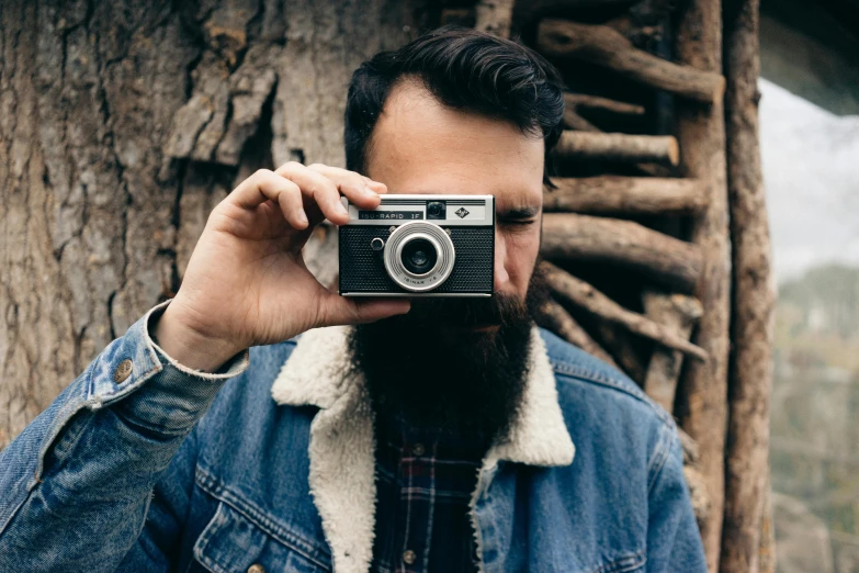 a man taking a picture with a camera, unsplash contest winner, photorealism, rugged beard, 1 9 7 0 s analog aesthetic, small beard, lumberjack